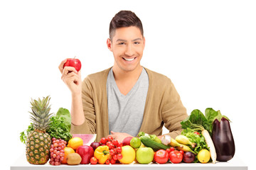 Obraz premium Handsome guy holding an apple on a table full of various food