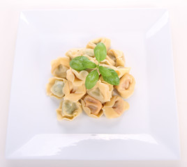 Tortellini on a plate decorated with fresh basil