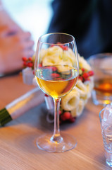 Glass with white wine and wedding flowers bouquet on table