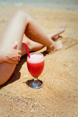 relaxing woman sitting on sand with cocktail 