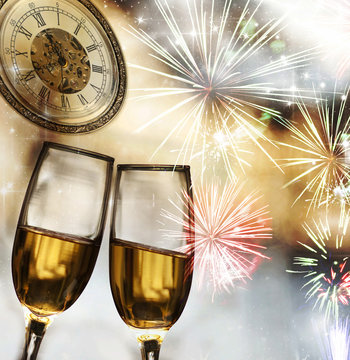 champagne glasses against clock and fireworks