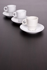 3 white coffee cups on brown table