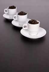 3 white cups with coffee beans on brown table