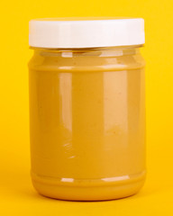 Delicious peanut butter in jar on yellow background