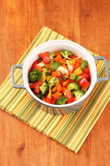 Vegetable stew in gray pot on color napkin on wooden background