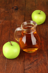 Full jug of apple juice and apple on wooden background