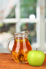 Full jug of apple juice and apple