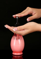 woman squeezing lotion on her hand, on black background