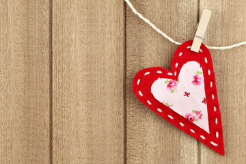 Red handmade felt heart clipped with clothespin on wood