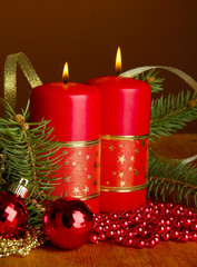 Two candles and christmas decorations, on brown background
