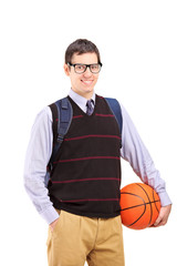 Smiling male student with school bag holding a basketball