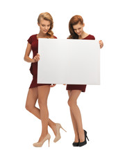 two teenage girls in red dresses with blank board