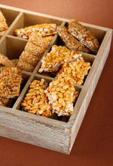tasty sweets (kozinaki)in wooden crate on brown background