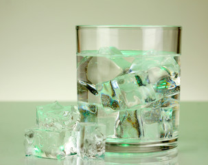 Ice cubes in glass on light green background