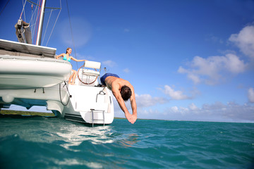 Man diving from catamaran deck into the sea