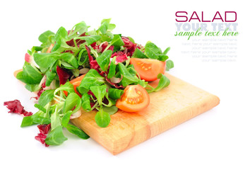 Fresh mixed salad with tomatoes on a wooden board