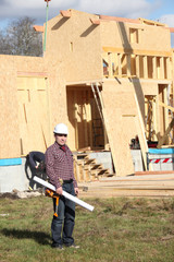 Architect stood by wooden house