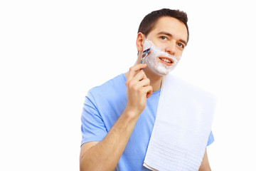 Young man at home shaving himself