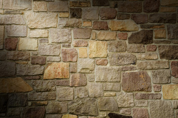 Masonry Wall of Multicolored Stone Lit Diagonally