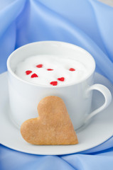 cup of hot milk decorated with sugar hearts and cookie