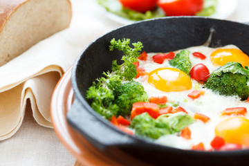Fried eggs in a pan with vegetables
