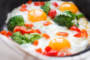 Fried eggs in a frying pan with broccoli and peppers