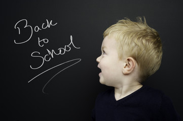 Smart young boy stood infront of a blackboard