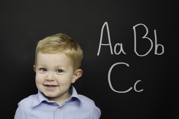 Smart young boy stood infront of a blackboard