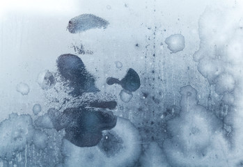 Male face print on frozen windows glass