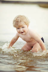 little funny boy playing in lake