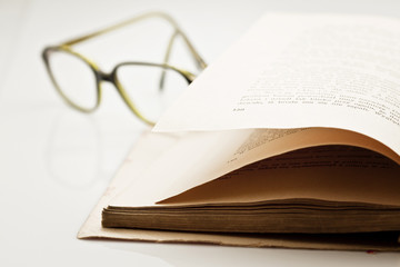 Closeup of old damaged book with glasses