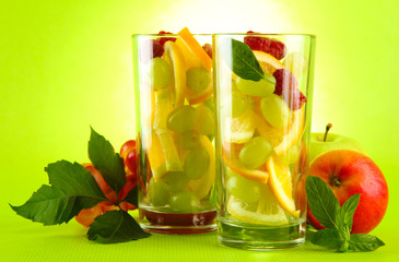 transparent glasses with citrus fruits, on grren background