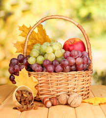Grape in basket with nuts on wooden table