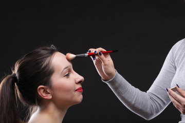 Obraz premium beautiful young brunette woman applying powder with a brush