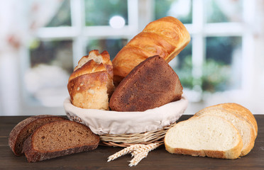 Fresh bread in basket on wooden table on window background