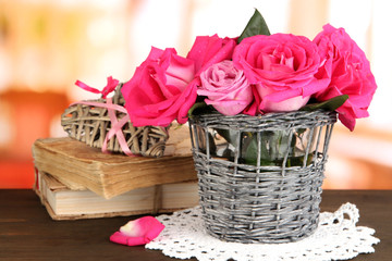 Fototapeta na wymiar Piękne różowe róże w wazonie na drewnianym stole na tle pokoju