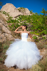 Fototapeta na wymiar wedding: Happy bride on cliff on background blue sea in summer