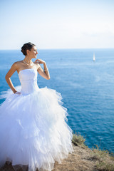 Fototapeta na wymiar wedding: Happy bride on cliff on background blue sea in summer