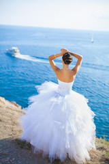 Fototapeta na wymiar ślub: Szczęśliwa panna młoda na klifie na tle błękitnego morza w lecie