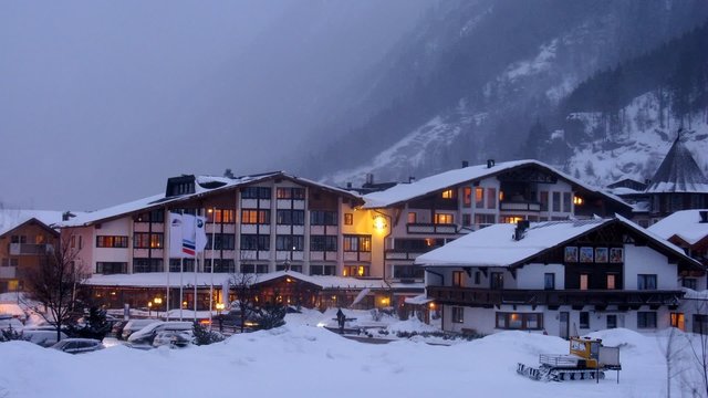 Hotel stands near road in valley where cars go and ly snow