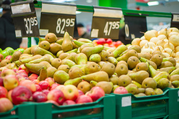 Bunch of pears and apples on boxes in supermarket