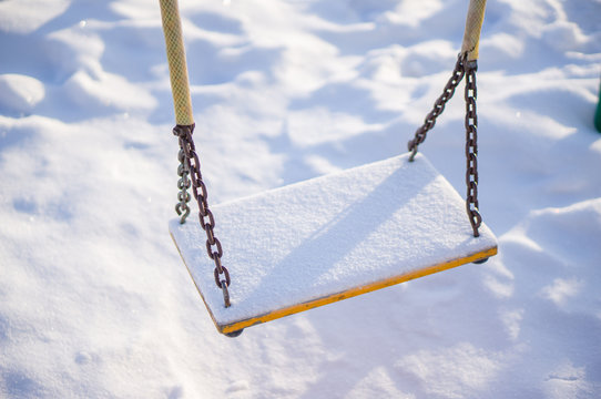 Kids chain swings on winter playground covered with snow