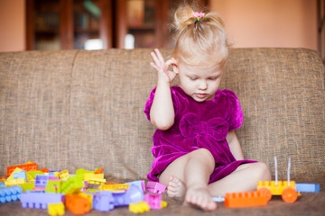 Cute little girl playing with blocks on the couch. Series
