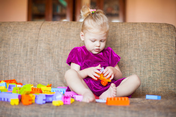 Cute little girl playing with blocks on the couch. Series