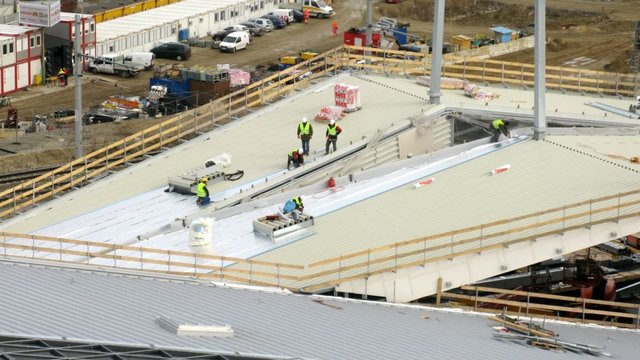 Workers lay an insulating cover on roof