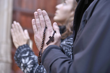 Hands of a praying couple holding prayer beads