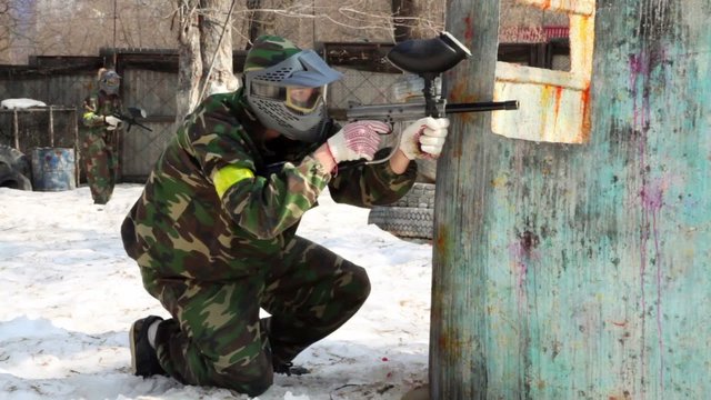 Couple teenagers sit in ambush with paintball gun and look out