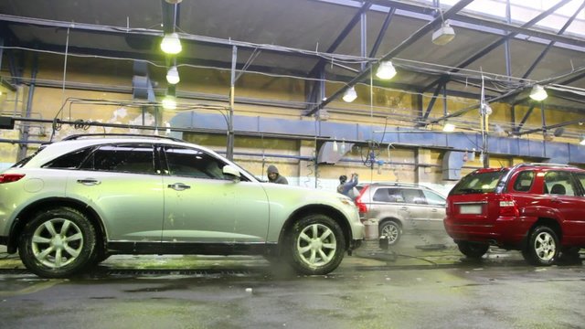 Workers wash with streams of water some cars on car wash