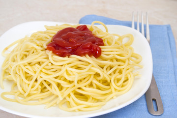 Spaghetti with ketchup in a bowl with a fork.