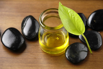 Fototapeta na wymiar bottle of aromatherapy oil with leaf on wooden board